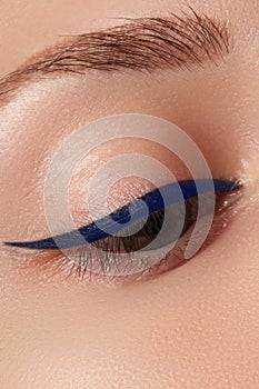 Beautiful model applying eyeliner close-up on eye. Make-up photo