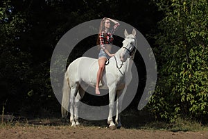 Beautiful model bareback ride her dressage horse in woods glade at sunset