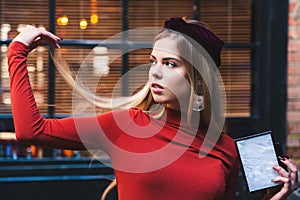 Beautiful model with blond hair poses against the backdrop of large windows and looks away. Skin retouching close-up