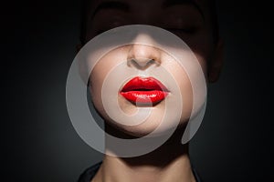 Beautiful model with bright red lips and face half covered in shadow