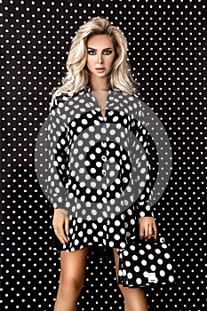 Beautiful model, dressed in a black pinup dress with white polka dots on a polka-dot background