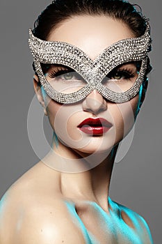 Beautiful Model with Fashion Lips Makeup wearing bright brilliant mask. Masquerade style woman. Holiday celebration look