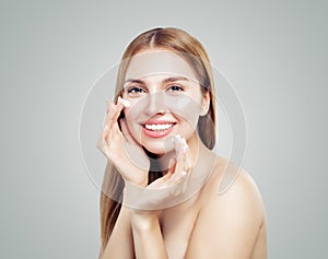Beautiful model girl applying cosmetic cream treatment on her face on white. Healthy woman portrait