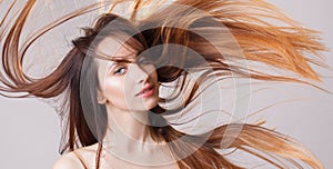 Beautiful model girl with shiny flying brown ombre straight long hair . Care and hair products .