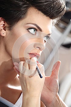 Beautiful model having lip liner applied by makeup artist