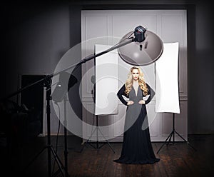 Beautiful model posing in black dress in photo studio.