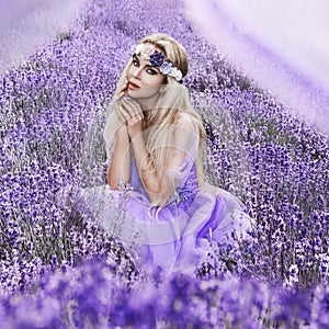Beautiful model walking in spring or summer lavender field in sunrise . Blond long haired girl in lavender field