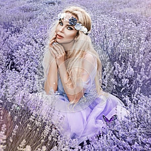 Beautiful model walking in spring or summer lavender field in sunrise . Blond long haired girl in lavender field