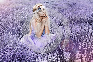 Beautiful model walking in spring or summer lavender field in sunrise . Blond long haired girl in lavender field