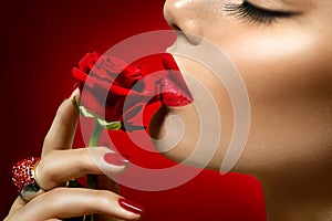 Beautiful model woman kissing red rose flower