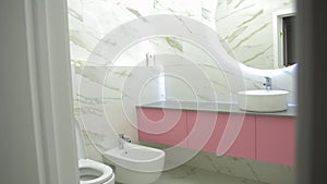 Beautiful modern bathroom interior with white porcelain tiles, sink, toilet and bidet. Modern illuminated mirror.