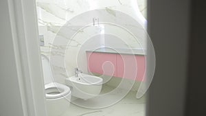 Beautiful modern bathroom interior with white porcelain tiles, sink, toilet and bidet. Modern illuminated mirror.