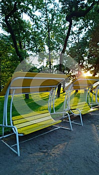 Beautiful modern bench-swing in a public Park of the city at sunset. Vertical view