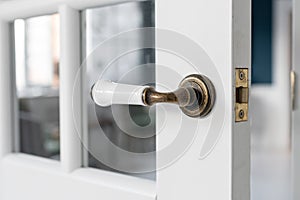 Beautiful modern door knob. Open, wooden front door from the interior of an upscale home with windows.