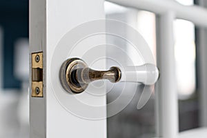 Beautiful modern door knob. Open, wooden front door from the interior of an upscale home with windows.