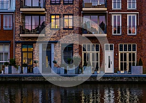 Beautiful modern dutch city architecture at night, terraced houses at the canal with balconies, Alphen aan den Rijn, The