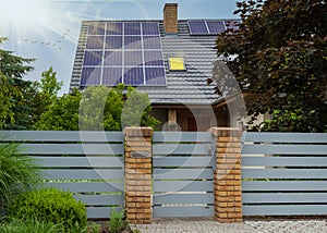 Beautiful modern house with solar panels. Clear sky, sun and lots of greenery photo