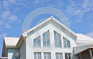 Beautiful modern house with white walls, white roof tiles and large panoramic home attic windows