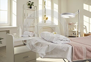 Beautician's office, spa salon, or massage room with bed, magnifying lamp and skin care products