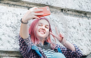 Beautiful modern smiling young female teenager with extraordinary hairstyle color taking selfie or video chatting via smartphone photo