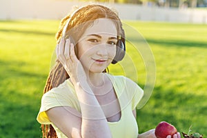 Beautiful modern woman listening to music with her headphones in autumn Sunny Park. Concept of good mood