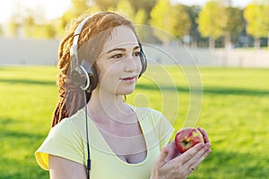 Beautiful modern woman listening to music with her headphones in autumn Sunny Park. Concept of good mood