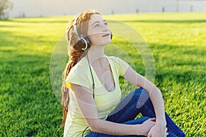 Beautiful modern woman listening to music with her headphones in autumn Sunny Park. Good mood and favorite music.