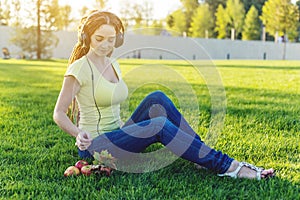 Beautiful modern woman listening to music with her headphones in autumn Sunny Park. Good mood and favorite music.