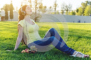 Beautiful modern woman listening to music with her headphones in autumn Sunny Park. Good mood and favorite music.