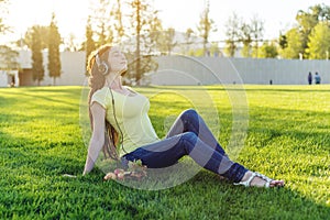 Beautiful modern woman listening to music with her headphones in autumn Sunny Park. Good mood and favorite music.