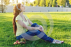 Beautiful modern woman listening to music with her headphones in autumn Sunny Park. Good mood and favorite music.