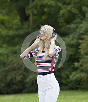 A beautiful modern young blonde with dark glasses.She holds the headphones on her head with a smile. photo