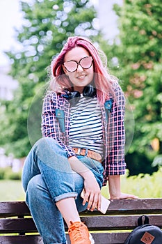 Beautiful modern young female teenager Portrait with extraordinary hairstyle color in a checkered shirt with wireless headphones