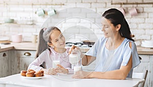 Beautiful mom and daughter drinking milk in kitchen together