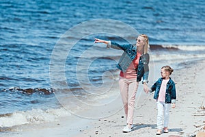 beautiful mom and daughter holding hands and walking on sea shore mother