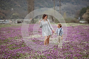 Beautiful mom holds her son`s hand on a walk