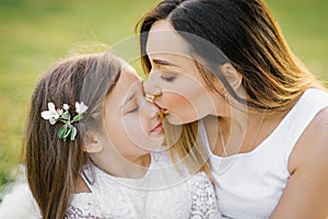 Beautiful mom kissing her little daughter on the nose