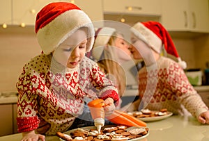 Beautiful mom and little sons decorating gingerbread Xmas cookies