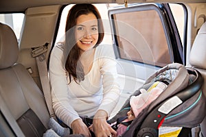 Beautiful mom putting baby on a child seat