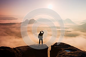 Beautiful moment the miracle of nature. Man stands on the peak of sandstone rock in national park Saxony Switzerland and watching