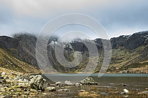 Beautiful moody Winter landscape image of Llyn Idwal and snowcapped Glyders Mountain Range in Snowdonia