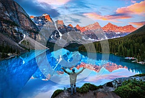 Beautiful Moraine Lake reflections with hiker in awe of golden sunrise over the Valley of the Ten Peaks in the Canadian Rockies