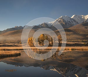 Beautiful morning autumn landscape, mountain lake on the background of snowy mountains