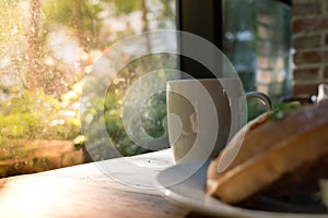 Beautiful morning with a white cup of coffee with blurred waffle on wooden table