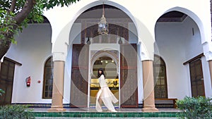 Beautiful Moroccan girl waving her white mantle in Picturesque Dar Si Said Riyad in Marrakech at sunset time