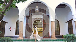 Beautiful Moroccan Girl Waving her white mantle in Picturesque Dar Si Said Riyad in Marrakech at sunset time