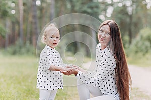 Beautiful mother with baby daughter are having fun in the forest, park. The concept of summer holiday. Mother`s, baby`s