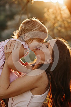 Beautiful Mother And Baby outdoors. Nature. Beauty Mum and her Child playing in Park together. Outdoor Portrait of happy