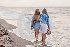 Beautiful mother and daughter at the beach enjoying summer vacation