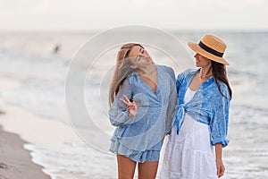 Beautiful mother and daughter at the beach enjoying summer vacation